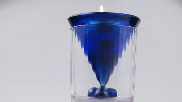 Burning candle in a glass white-blue candlestick on a white background