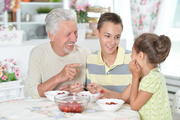 Portrait of happy family eating fresh strawberries