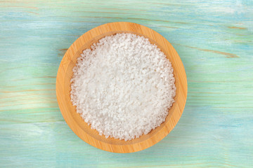 A bowl of sea salt, shot from above on a teal blue background with copy space