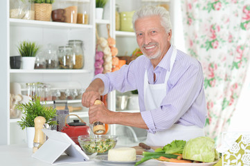 Obraz na płótnie Canvas Senior man preparing dinner in kitchen