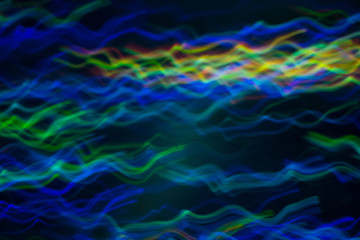 Fototapeta na wymiar Blurred blue green lines on dark background. Neon lights in motion. Lens flare glow.