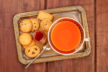 Danish butter cookies on a vintage tray with a cup of tea and jam, shot from the top on a dark rustic wooden background