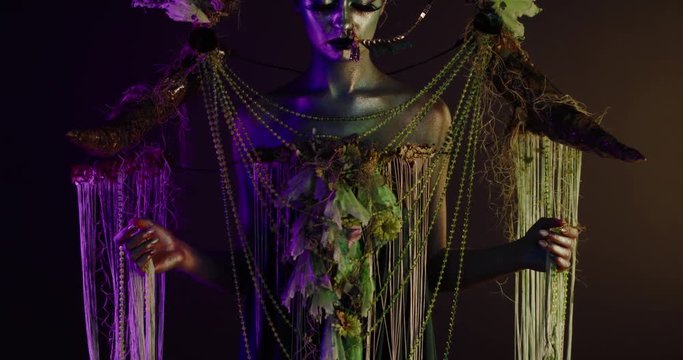 Portrait of beautiful female with complex floral make-up posing in creative lighting. Body painting fashion project. Model and property released. 4K UHD RAW FOOTAGE