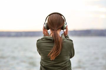 Young woman listening to music near river