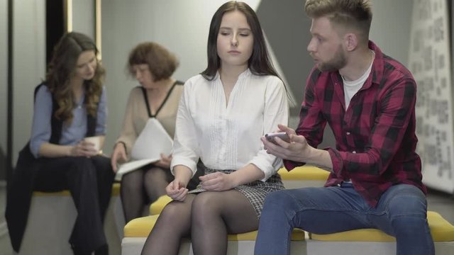 The guy gets on the phone the news from which the girl loses consciousness. Young woman faints in the workplace. Colleagues are scared and worried. First-aid colleagues in the office.