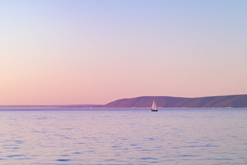 beautiful landscape with yacht. mountains in the background. purple pink tinted.
