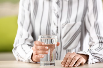 Woman drinking water in office, closeup