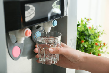 Woman pouring water from cooler into glass, closeup
