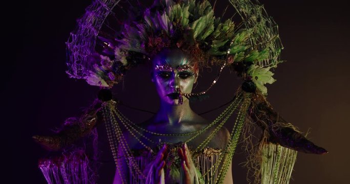 Portrait of beautiful female with complex floral make-up posing in creative lighting. Body painting fashion project. Model and property released. 4K UHD RAW FOOTAGE