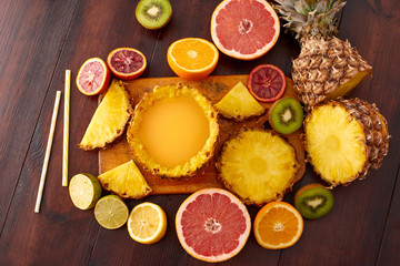 Fototapeta na wymiar Fresh fruit juice with exotic fruits on a wooden brown table. A composition made of grapefruit, lemon, lime, pineapple, orange. Top wiev. 