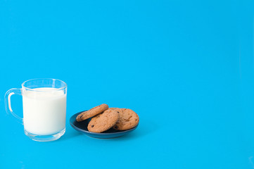 cookies and glass of milk on blue background. oatmeal cookie with pieces of chocolate