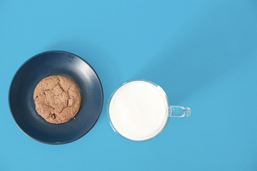 cookies and glass of milk on blue background. oatmeal cookie with pieces of chocolate
