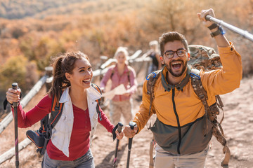 Group of happy hikers walking on the glade and chatting. In foreground couple leading the group....