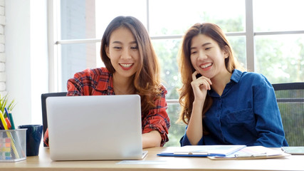  Two young asian women working with laptop computer at home office with happy emotion moment, working at home, small business, office casual lifestyle concept