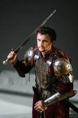 Medieval man knight in armor and weapon on dark background. Portrait of the knight