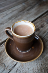 Cup of White Tea in earthen ware mug with matching saucer on wooden table.  Rustic shabby chic look