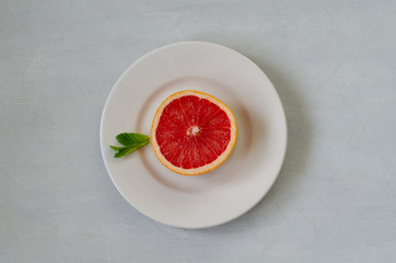 A slice of grapefruit on a white plate.