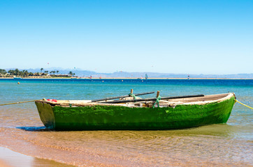 Obraz premium Old wooden fishing boat in the sea on the background of the beach with palm trees in Egypt. Dahab