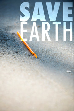 Save Earth awareness on Earth day and every day. Orange straw found left trashed on the beach. A starting point of the environment problem.