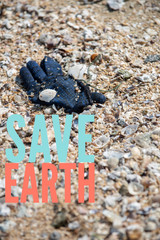 Save Earth awareness on the Earth day. A deep blue winter yarn glove found trashed on the beach surrounded with sea shells.