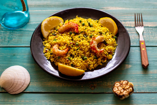 Paella with shrimp on a blue wooden background - Powered by Adobe