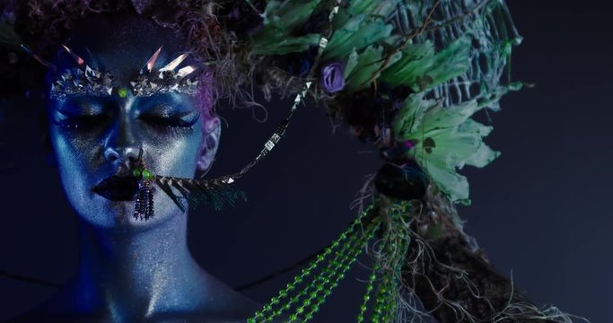 Portrait of beautiful female with complex floral make-up posing in creative lighting. Body painting fashion project. Model and property released. 4K UHD RAW FOOTAGE