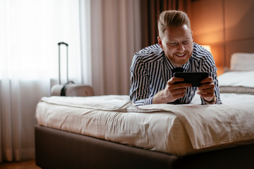 Businessman relaxing after meetings. Manager resting after travelling. Man checking his wifi connection at a hotel room.