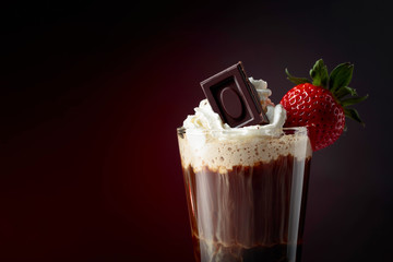 Chocolate drink with whipped cream, strawberry and pieces of black chocolate.