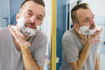 Guy shaving his beard in bathroom