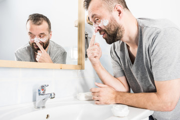 Man applying moisturizer cream in bathroom