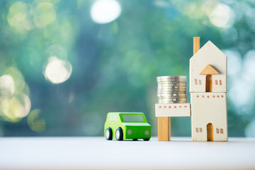 Close up of coins and toy home toy car on wooden table on blur background