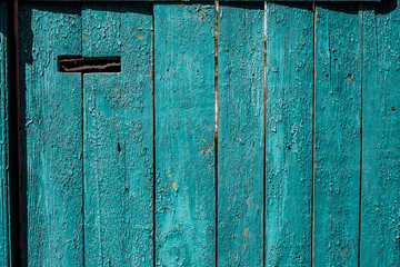 Old blue painted wooden door with mail hole. Horizontal texture of cracked paint on wood