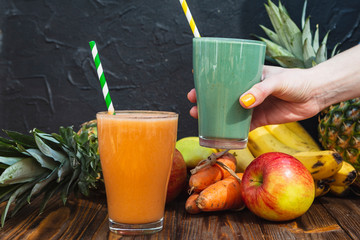 Blended green and orange smoothie with ingredients on wooden table