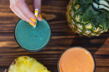 glass is filled with fresh and useful smoothie made from spicy juicy vegetables and fruits. Drink is sitting on a wooden table near the ingredients from which it is cooked illuminated by warm daylight