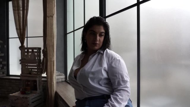 Model plus size drinks juice near the window