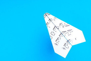 Paper jet /paper airplane made of a music score. Music score paper plane on blue.