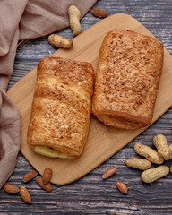 Delicious puff. Sweet bun. Peanuts. Almonds. Wood background. Nuts. Top view. Space for a text.