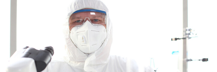 Male scientist wearing white protective suit and mask