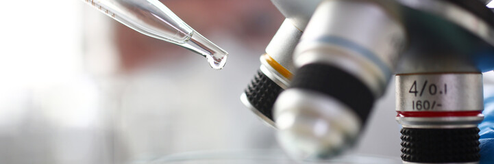 Scientist dosing a drop with pipet to exam with microscope