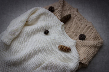  White and beige, winter, knitted sweaters handmade. Sweaters on a gray background.