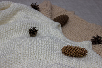  White and beige, winter, knitted sweaters handmade. Sweaters on a gray background.