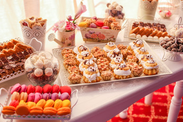Delicious cnady bar with colored macaroons, cupcakes and other sweets