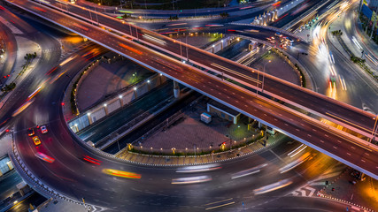 Road roundabout intersection in the city at night with vehicle car light movement, Aerial view.