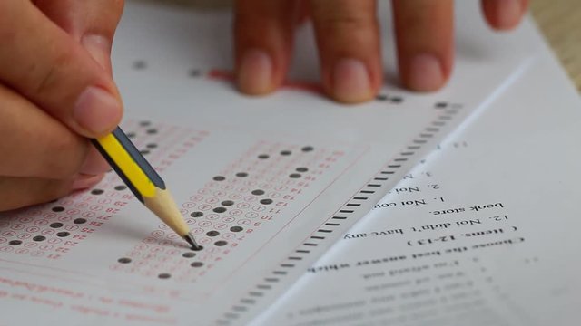 Education school test concept : Hands student holding pencil for testing exams writing answer sheet or exercise for taking fill in admission exam multiple carbon paper computer at university classroom