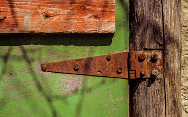 Rusty Door hinge on green painted wood door with cracked and scratch. Horizontal grunge texture