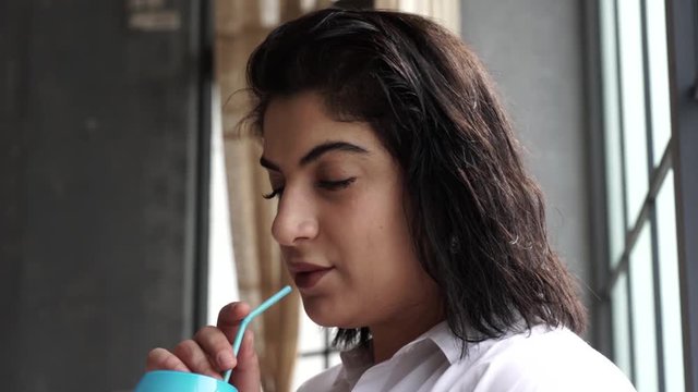 Model plus size drinks juice near the window