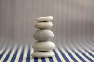 Harmony and balance, pebble rock cairn, simple poise stones on white and blue striped background, rock zen sculpture, one tower