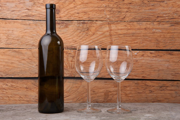 a bottle of wine and near it two glasses on wooden background
