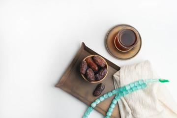 Ramadan Kareem Festival, Dates on wooden bowl with cup of black tea and rosary on white isolated background