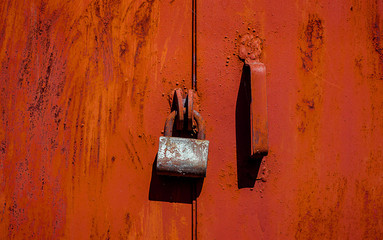 Rusty old padlock on red metal door with cracked and scratch. Horizontal grunge texture